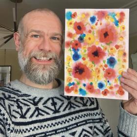 Olaf Falafel holding up watercolour flowers artwork